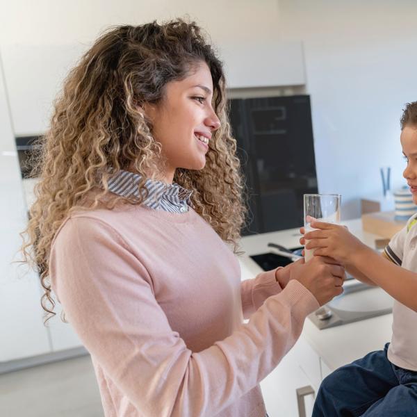 Mother handing a glass of milk to her son