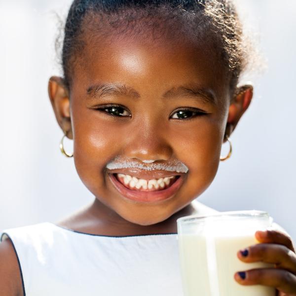 image of smiling child holding a glass of milk
