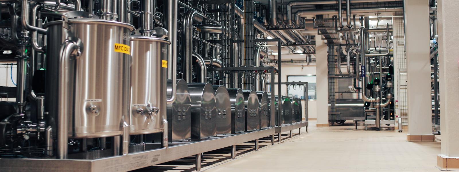 Static image of a factory floor, with silver machinery in view. 