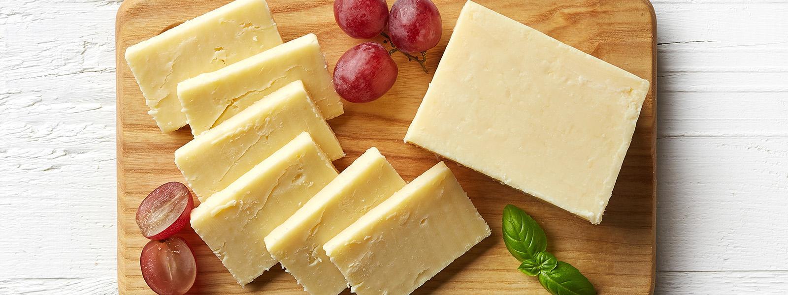 board with different types of cheese and grapes